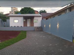 une maison blanche avec une clôture et une allée en briques dans l'établissement Trentino 66 - Hospedagem em Ijuí, casa agradável com estacionamento, à Ijuí