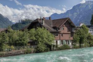 a house next to a river with mountains in the background at CityChalet historic in Interlaken