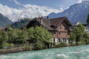 ein Haus neben einem Fluss mit Bergen im Hintergrund in der Unterkunft CityChalet historic in Interlaken