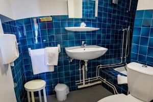 La salle de bains est pourvue de carrelage bleu, d'un lavabo et de toilettes. dans l'établissement Hotel Le Boischaut - Citotel Chateauroux, à Châteauroux