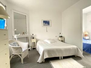 a white bedroom with a bed and a chair at Villa ROMEO , 250M de la plage in Saint-Georges-de-Didonne