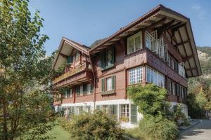 Cette grande maison en bois possède des fenêtres sur une colline. dans l'établissement CityChalet historic, à Interlaken