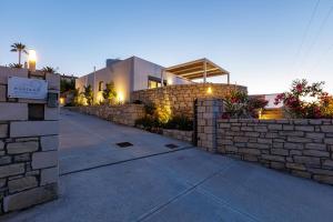 a building with a stone wall next to a sidewalk at EVELAND ACCESSIBLE VILLAS in Sfakaki