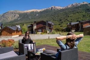 two women sitting on a patio with mountains in the background at Galileo Boutique Hotel in San Carlos de Bariloche