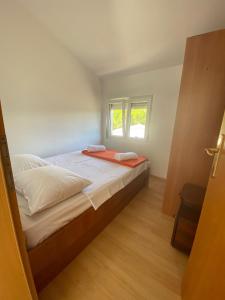 Schlafzimmer mit einem Bett und einem Fenster in der Unterkunft Apartmani Marija in Molat
