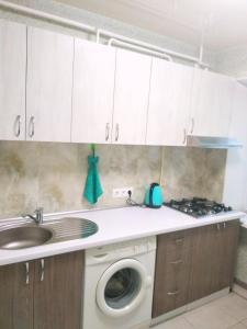 cocina con fregadero y lavadora en Светлые апартаменты в 100м от Софиевского парка, en Uman