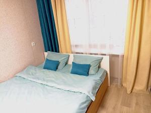 uma cama com almofadas azuis num quarto com uma janela em Светлые апартаменты в 100м от Софиевского парка em Uman