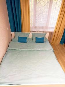 a bed with blue pillows in a room with a window at Светлые апартаменты в 100м от Софиевского парка in Umanʼ