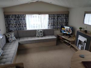 a living room with a couch and a television at Lovely Static 6 Bed Caravan at Billing Aquadrome in Great Billing