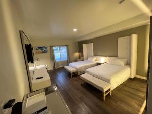 a hotel room with two beds and a television at ASPIRE INN & SUITES Orange in Orange