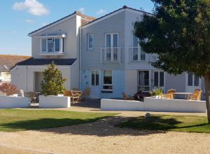 une maison avec des chaises et des tables dans une cour dans l'établissement West Bay Cottages Yarmouth Isle of Wight, à Yarmouth