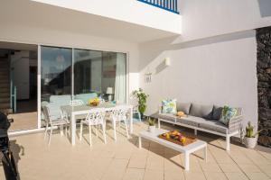 Una sala de estar con un sofá, una mesa y sillas. en CALERO DREAM by Buenavilla, en Puerto Calero