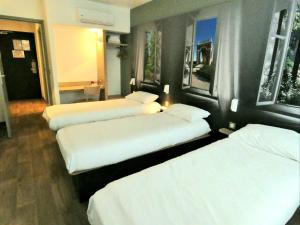 un grupo de 3 camas en una habitación de hotel en B&B HOTEL Cambrai, en Cambrai