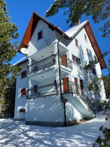 Un edificio de apartamentos blanco con balcones y nieve. en Apartments Aurora, en Risovac