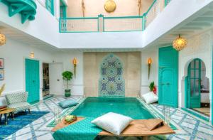 una piscina al centro di una stanza con porte blu di riad paradis blanc a Marrakech