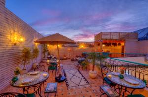 - un balcon avec des tables, des chaises et un parasol dans l'établissement riad paradis blanc, à Marrakech