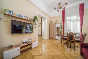 een woonkamer met een tafel en een tv aan de muur bij Vintage Apartment in Pécs +31 foto's