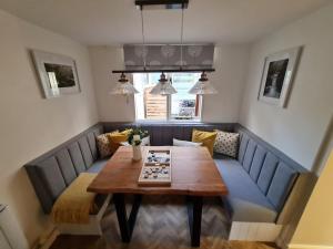 a dining room with a wooden table and blue chairs at Old Post Office - Hot Tub, Real Fire, Cumbrian Lakes Coastal Cottage in St Bees