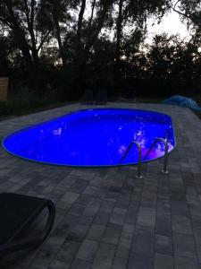 a blue swimming pool with two chairs around it at Black Horse in Pasłęk