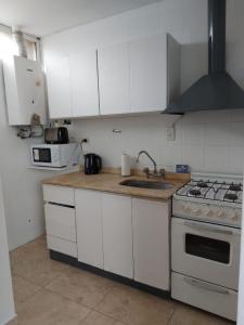 a kitchen with white cabinets and a sink and a stove at Quinta Park in Mendoza