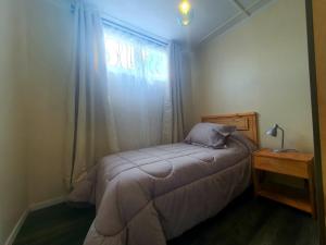 a small bedroom with a bed and a window at Álamos de Llancahue in Valdivia