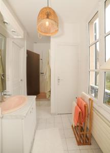 een witte badkamer met een wastafel en een spiegel bij Le Jardin Cathedrale in Chartres