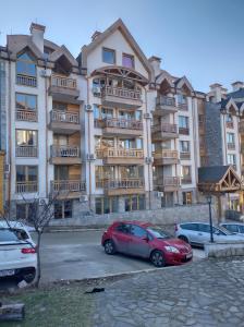 a large apartment building with cars parked in a parking lot at St John Park Boutique room Gero in Bansko +7 photos