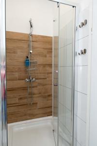 a shower in a bathroom with a wooden wall at Studio apartman Rossa in Daruvar