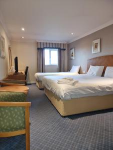 a hotel room with a bed, desk, chair and a lamp at Kegworth Hotel & Conference Centre in Castle Donington