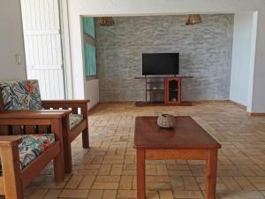 ein Wohnzimmer mit einem Sofa und einem TV in der Unterkunft Casa de praia, Tabuba, Barra de Santo Antônio - AL in Barra de Santo Antônio