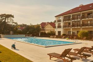 una grande piscina con sedie e un edificio di SeaYou Yellow House a Rogowo