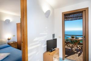 a bedroom with a bed and a tv and a balcony at Emotion in Praiano