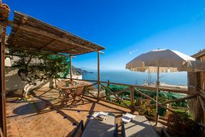 a patio with a table and an umbrella and the ocean at Emotion in Praiano