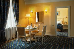una habitación de hotel con una mesa y sillas y un dormitorio en Hotel Volgograd, en Volgograd