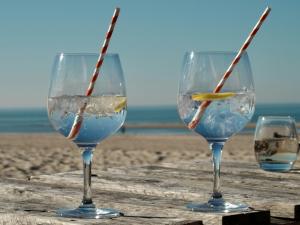 three wine glasses sitting on a table on the beach at Klinket Zoutelande in Zoutelande
