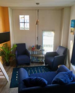 a living room with a blue couch and two chairs at Klinket Zoutelande in Zoutelande