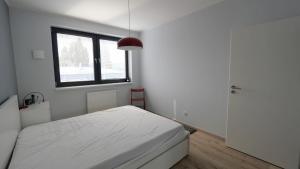 a white bedroom with a bed and a window at Air-conditioned, 2 room apartment with terrace in Bratislava