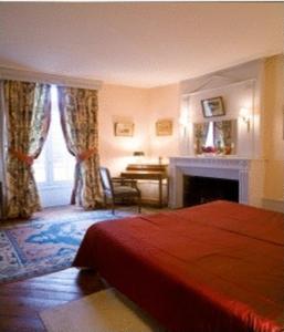 1 dormitorio con cama roja y chimenea en Château de Sarceaux en Alençon