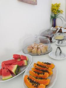 a table with three plates of fruit on it at Estrela Azul Guest House Búzios in Búzios