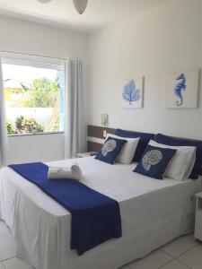 a bedroom with a large bed with blue and white pillows at Estrela Azul Guest House Búzios in Búzios