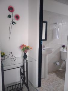 baño con lavabo y jarrón de flores en Apartamentos El Caudal, Villavicencio, en Villavicencio
