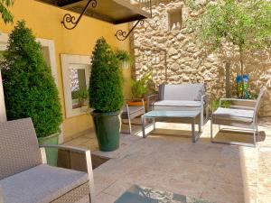 a patio with chairs and tables and a stone wall at La Maison du Courtil, Amande-Olive in Moustiers-Sainte-Marie