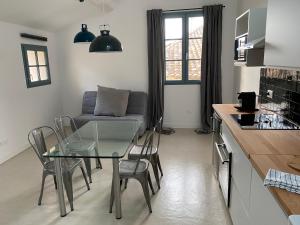 eine Küche und ein Wohnzimmer mit einem Glastisch und einem Sofa in der Unterkunft La maison Barberousse in Gruissan