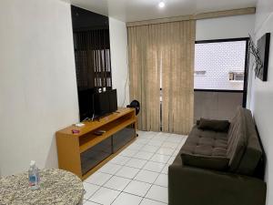 een woonkamer met een bank en een televisie bij Perto da Praia e Piscina na cobertura in Maceió