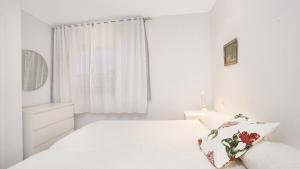 ein weißes Schlafzimmer mit einem Bett und einem Fenster in der Unterkunft Anc 04 - Llafranc in Llafranc