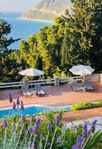 a pool with chairs and umbrellas and the ocean at Myrto Homes Lefkada Agios Nikitas Greece in Agios Nikitas