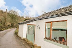 una casetta bianca con una finestra e una strada di Camerton Hall Cottage a Workington