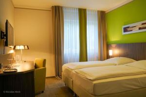 a hotel room with two beds and a green wall at Hotel Ambiente Walldorf in Walldorf