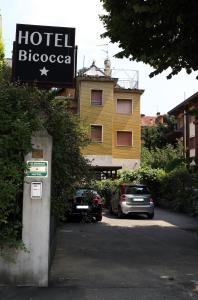 un cartello biococco dell'hotel e le auto parcheggiate in un parcheggio di Hotel Bicocca a Milano