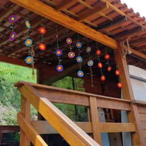 a wooden deck with colorful chandeliers hanging from a roof at Pousada Recanto Viva a Vida in Domingos Martins